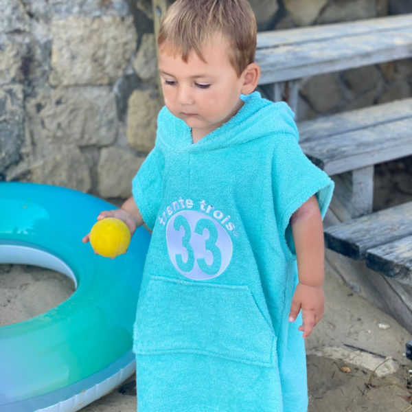 Un poncho turquoise pour bébé, estampillé "trente-trois" de la marque régionale 33.