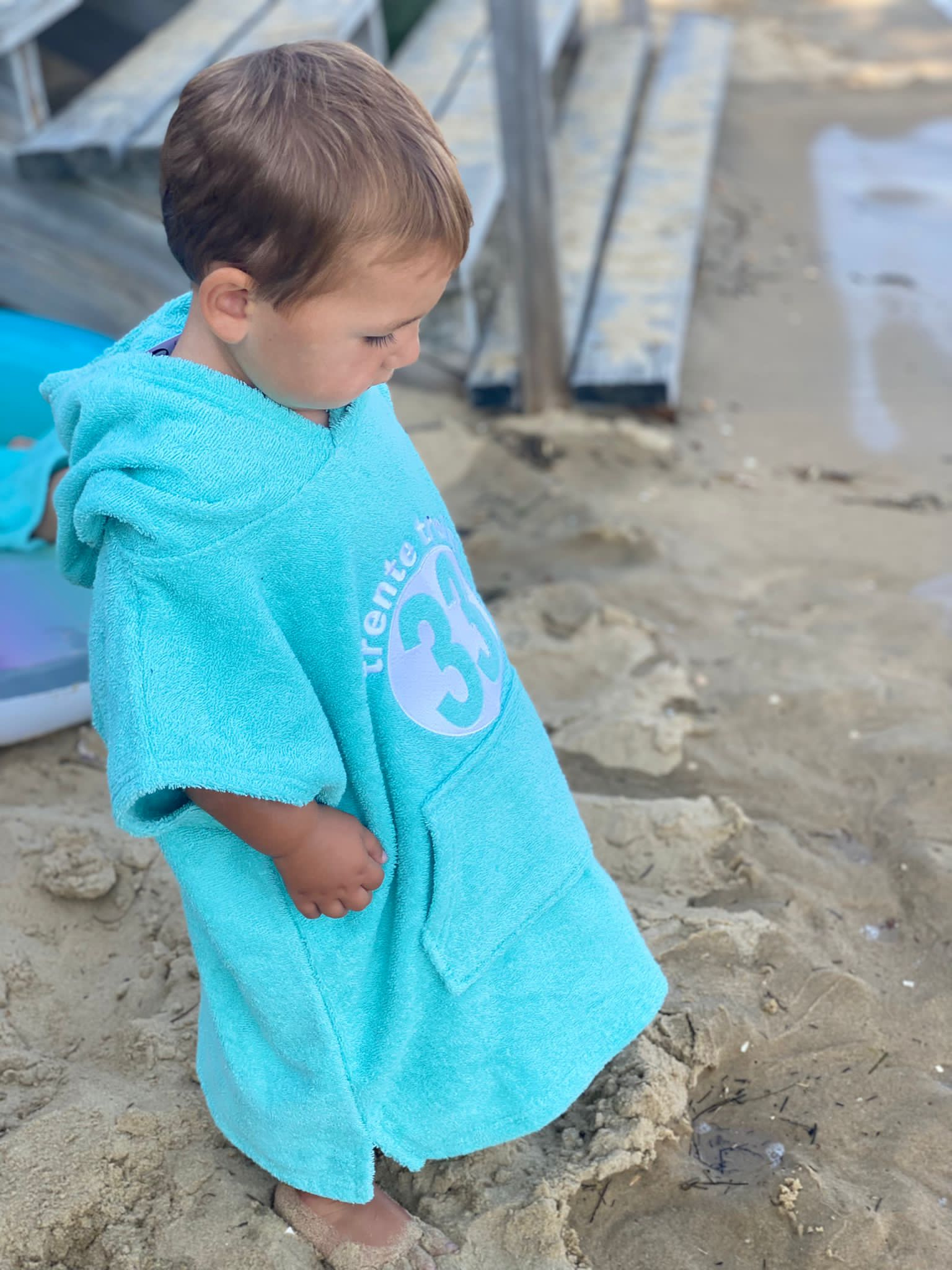 Un poncho turquoise pour bébé, estampillé "trente-trois" de la marque régionale 33.