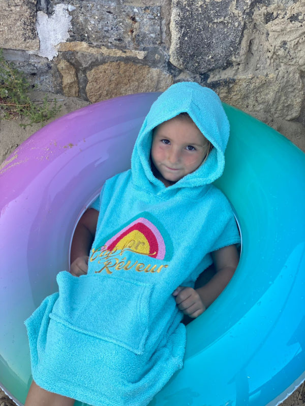 Un poncho turquoise pour bébé, estampillé "Cap for rêveur" de la marque régionale 33.