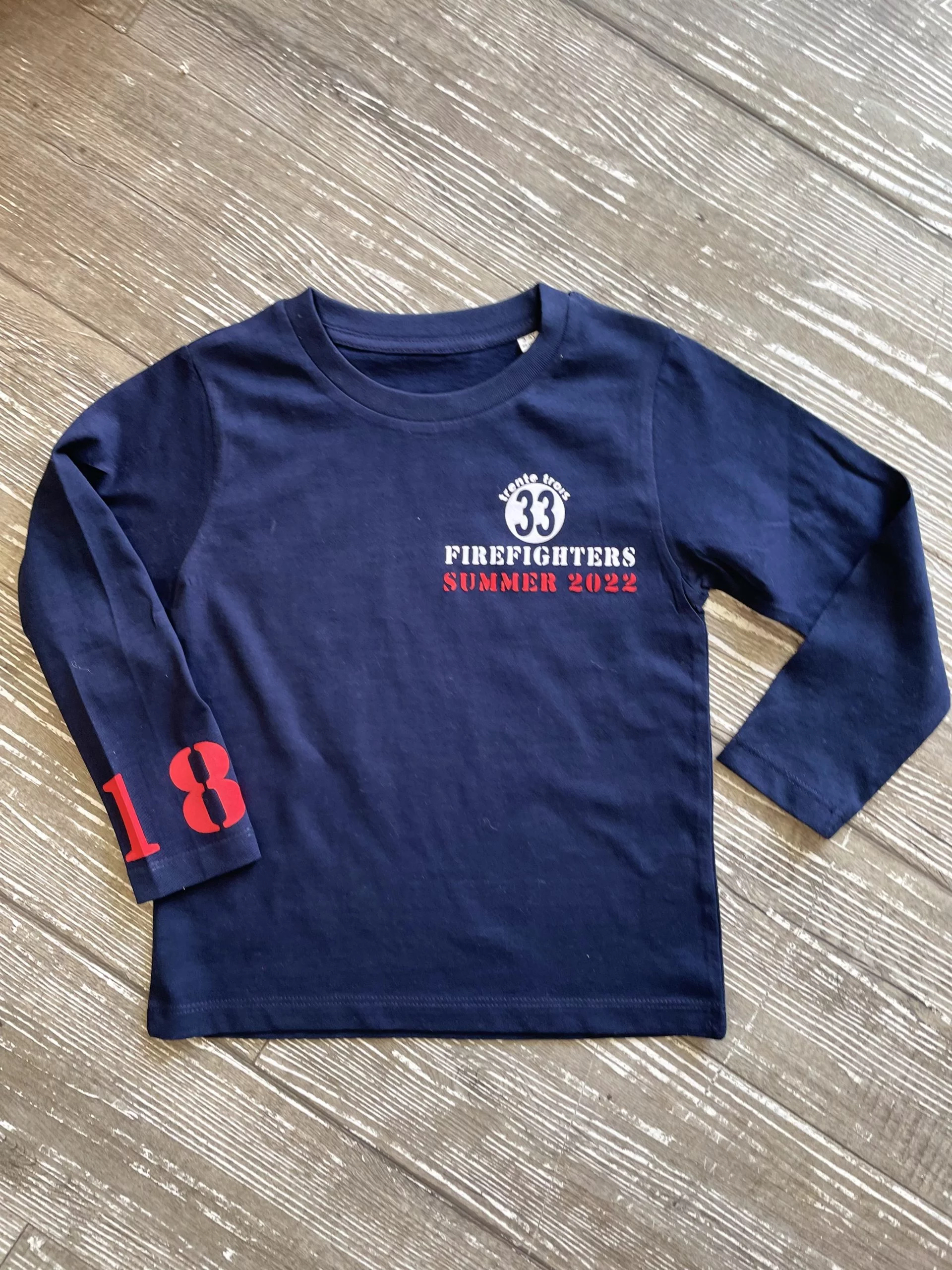 Un tee-shirt marine à manches longues pour garçon, estampillé "Firefighters" de la marque régionale 33.