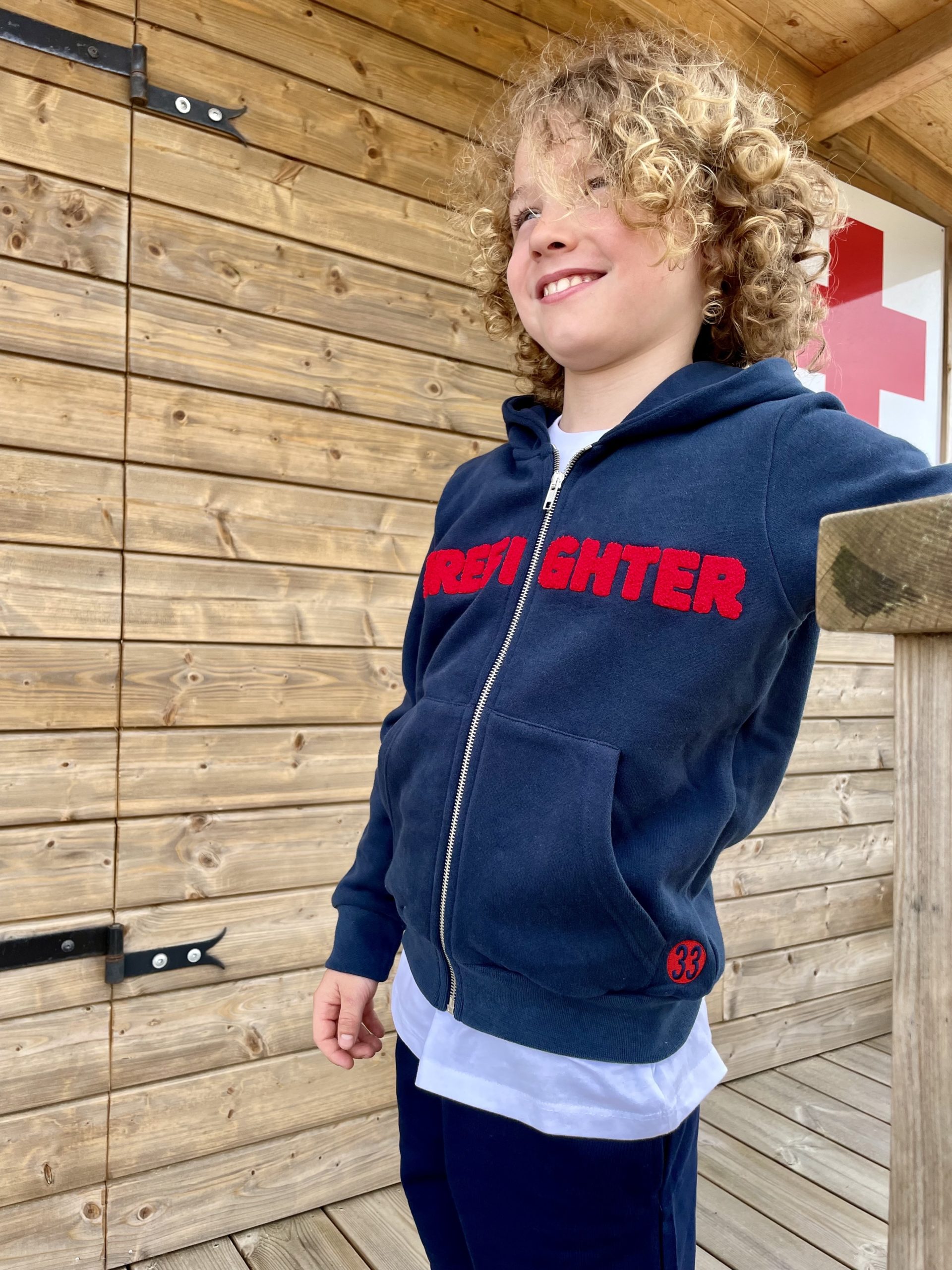 Une veste zippée marine pour garçon, estampillée "Fire Fighter" de la marque régionale 33.