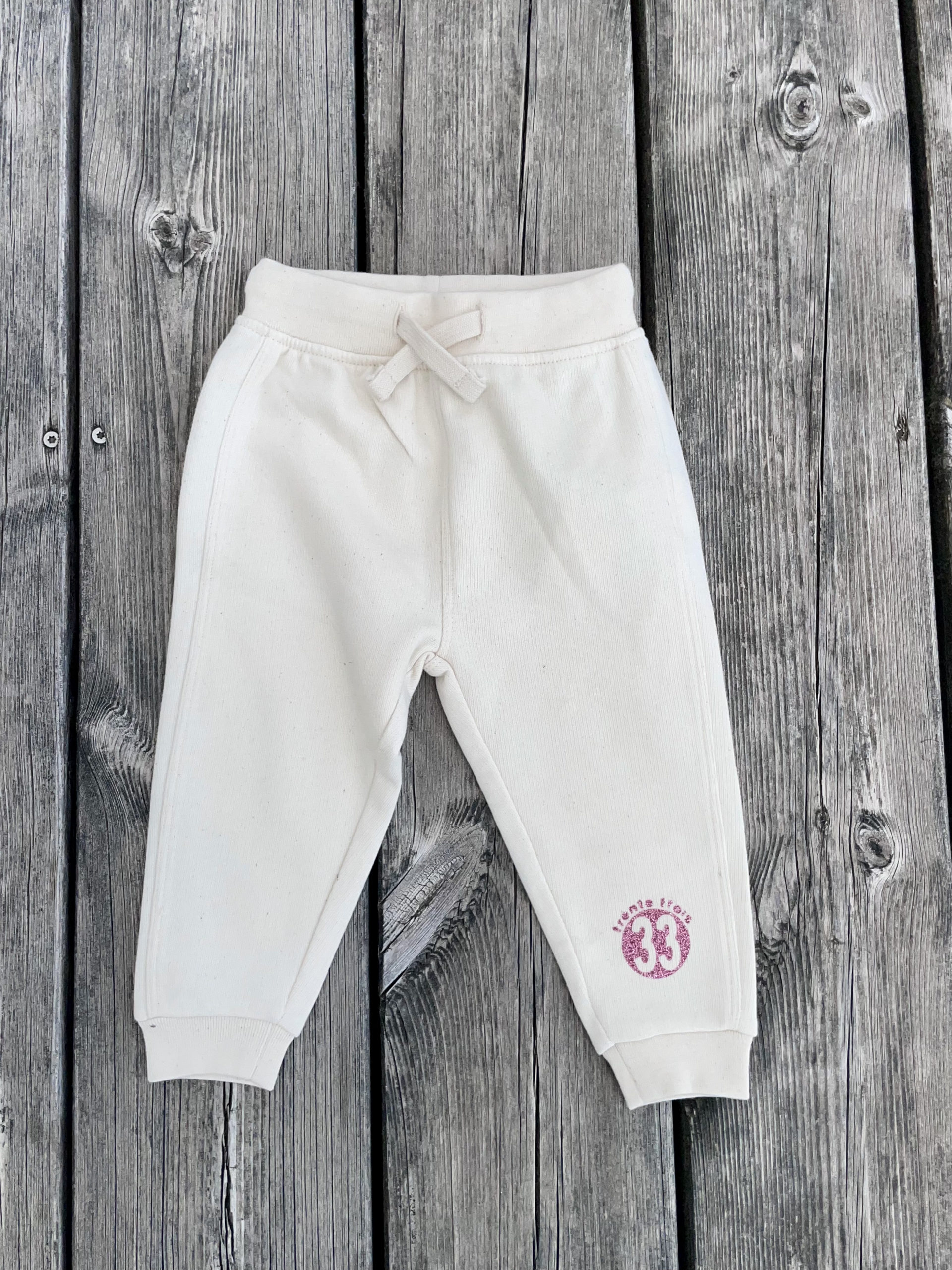 Un jogging beige pour bébé, estampillé "Crevette du bassin" de la marque régionale 33.