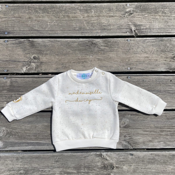 Un sweat écru pour bébé, estampillé "Mademoiselle du cap" de la marque régionale 33.