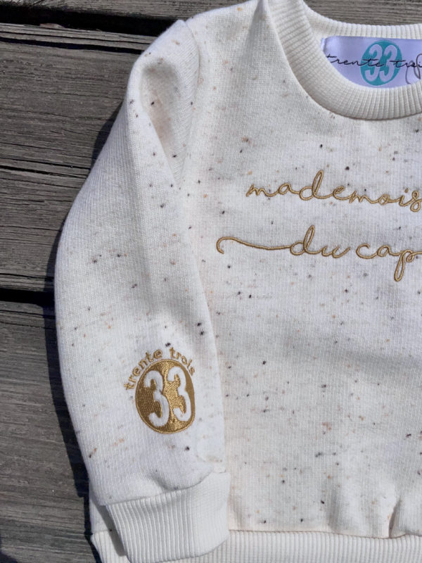Un sweat écru pour bébé, estampillé "Mademoiselle du cap" de la marque régionale 33.
