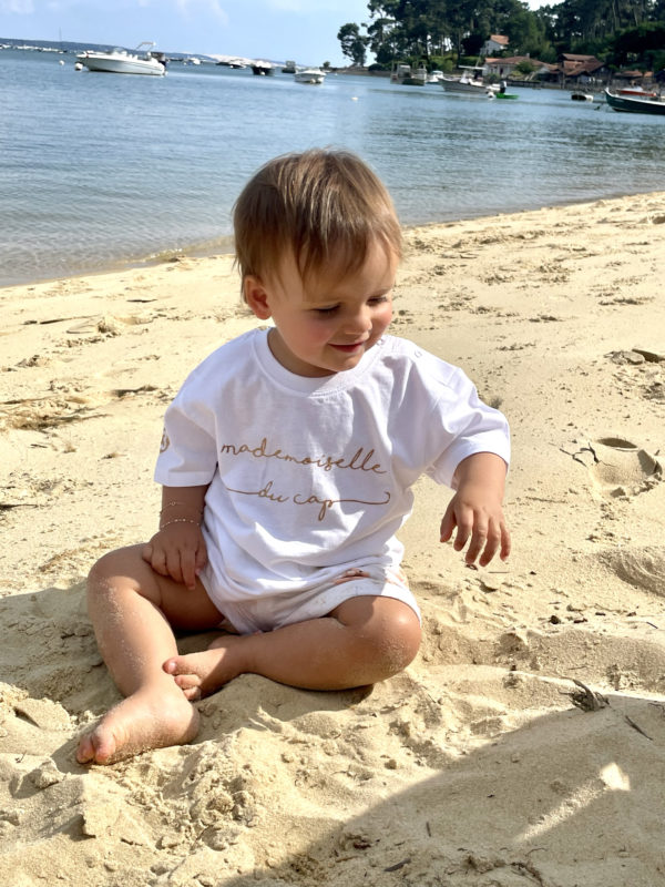Un tee-shirt blanc pour bébé, estampillé "Mademoiselle du cap" de la marque régionale 33.