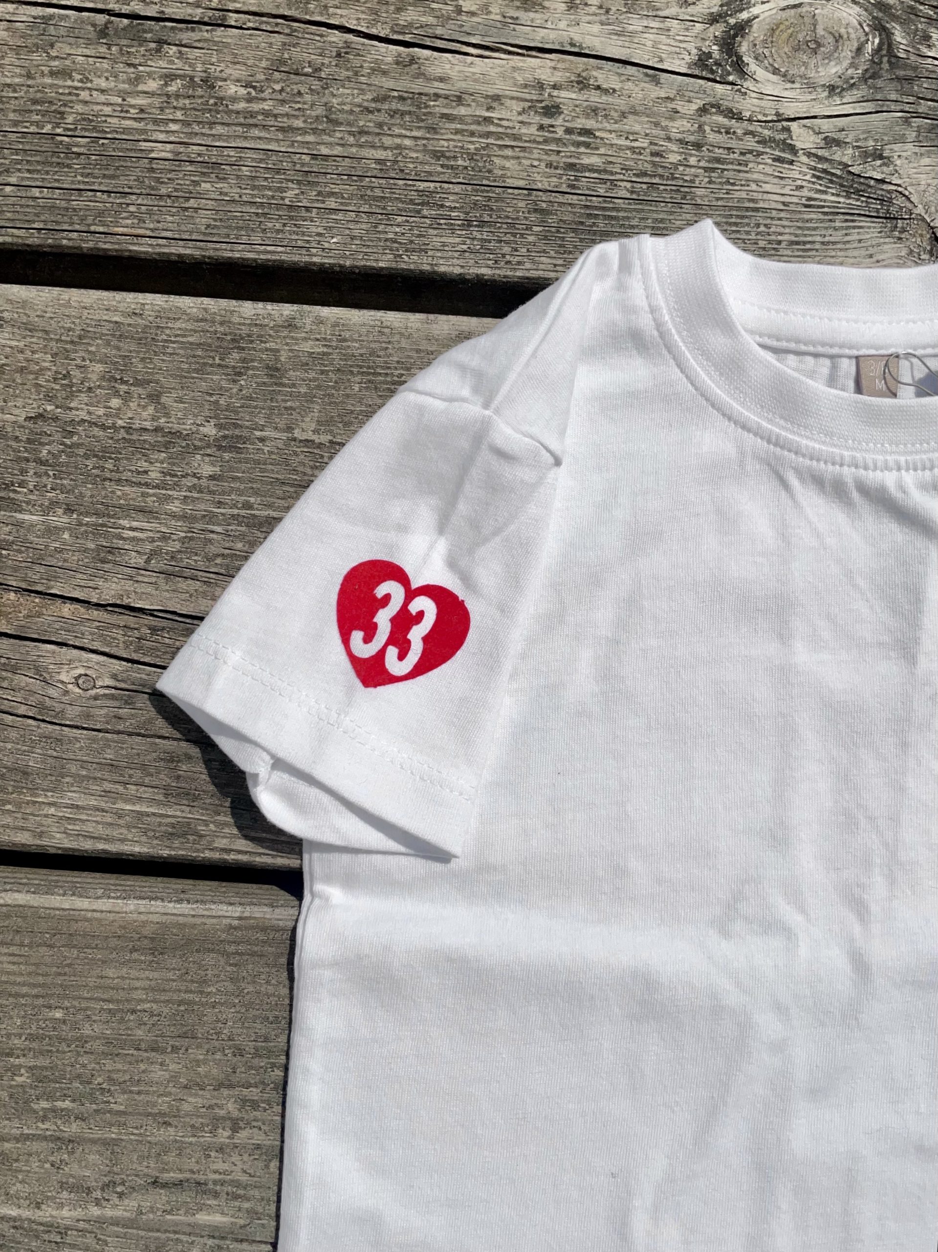 Un tee-shirt blanc pour bébé, estampillé "Amour à l'ouest" de la marque régionale 33.