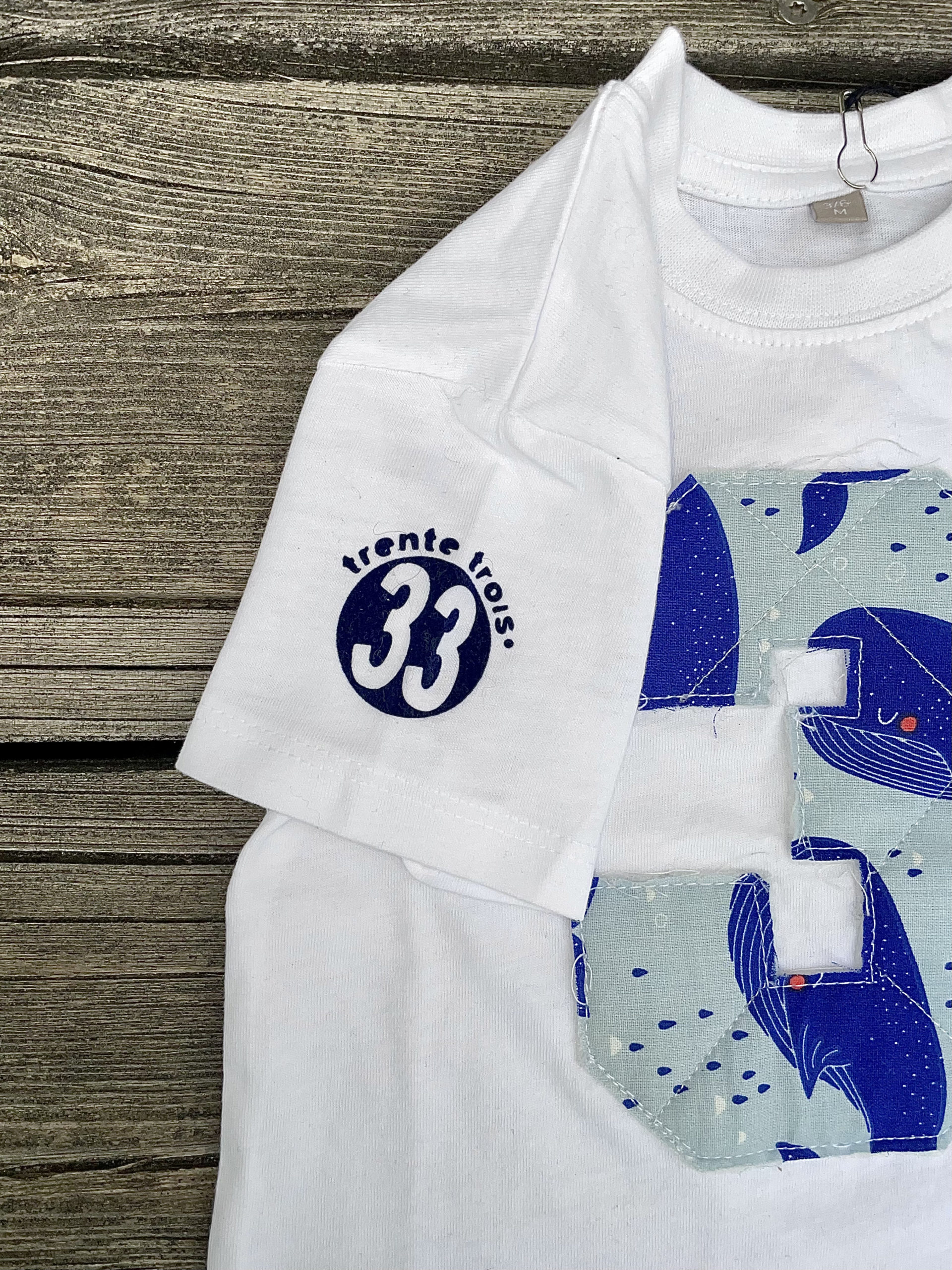 Un tee-shirt blanc pour bébé, de la marque régionale 33.