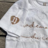 Un tee-shirt blanc pour bébé, estampillé "Mademoiselle du cap" de la marque régionale 33.